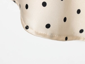 Gros plan du tissu satiné à pois et détails de couture sur cette jupe en soie champagne