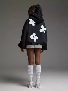 Detailed back view of black oversized floral print hoodie featuring three white flower motifs