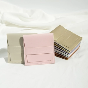 Close-up of PU leather jewelry pouches in pink, grey and gold with snap button and logo