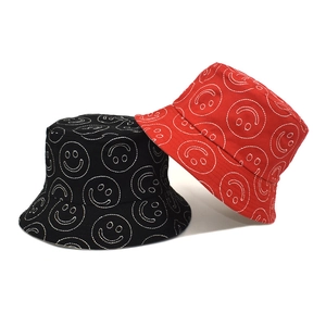Black and red cotton bucket hats with white embroidered smileys on a clean white background