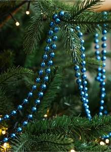 Blue electroplated bead chain decoration draped on a green Christmas tree branch