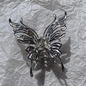 Detailed close-up of a silver liquid metal butterfly hair claw clip on white paper