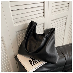 Close-up of a black textured leather tote bag on a sofa with minimalist modern details
