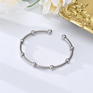 Detailed close-up of a silver stainless steel cable wire cuff bracelet with polished beads