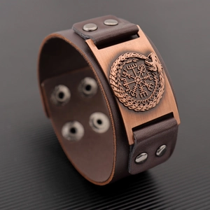 Detail of a brown leather bracelet featuring an embossed viking compass and ouroboros charm