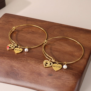Close-up of gold MOM heart pendant bracelet set with elegant pearl accents on wood
