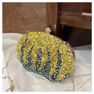 Detail of evening clutch bag with yellow and green sequins on beige satin background