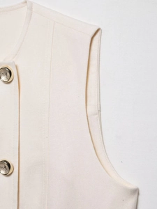 Detail of cream sleeveless vest showing woven texture and gold-edged round buttons