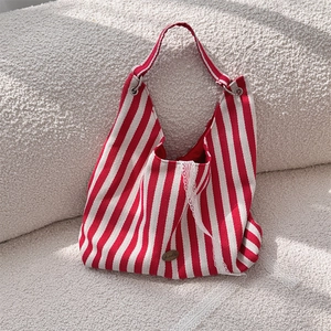 Détail du sac cabas en toile à rayures rouges et blanches avec dentelle et logo
