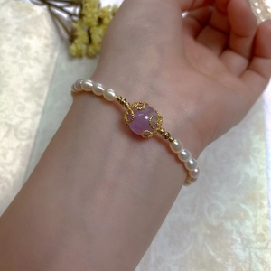 Detail of baroque pearl bracelet with purple gemstone and gold-plated floral filigree
