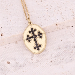 Golden necklace featuring an oval pendant with a black gemstone cross on beige stone