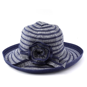 Détail du tissage rayé bleu et gris du chapeau de paille avec fleur décorative latérale