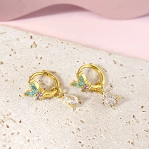 Luxurious gold butterfly drop earrings with colorful crystals on a textured stone surface
