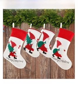 Set of four white and red embroidered Nordic Christmas gnome stockings on pine branches