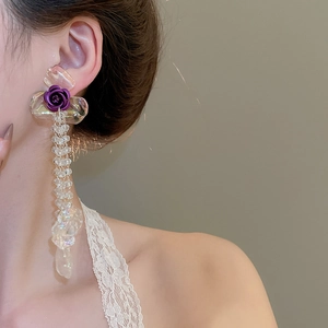 Close-up of a floral earring with purple rose and transparent beaded tassels on model