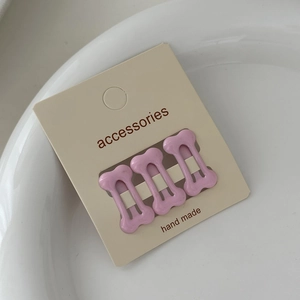 Macro shot of three pink bone-shaped mini hair clips on a handmade accessories card