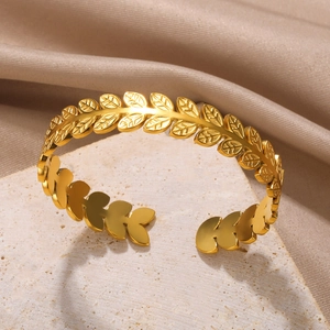 Detailed view of a gold laurel leaf open cuff bracelet on elegant silk fabric