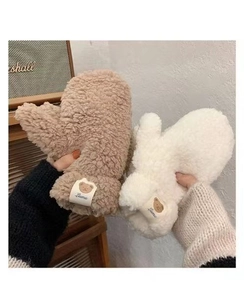 Detail of plush lamb wool mittens in camel and beige featuring cute bear labels