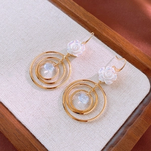 Boucles d'oreilles dorées avec clous de roses blanches et zircones en cercles dorés