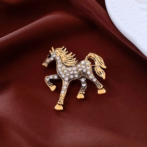 Macro shot of gold horse brooch with sparkling rhinestones on deep red silk fabric
