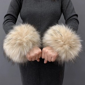 Detailed close-up of beige and brown faux fur wrist cuffs worn on a model