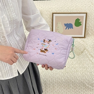 Close-up of quilted lavender cosmetic bag featuring cartoon dog embroidery and side hook