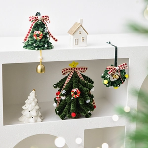 Mini velvet Christmas tree and white ceramic house set on a minimalist white shelf