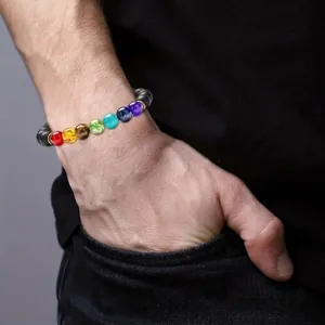 Seven Chakra energy beaded bracelet with natural volcanic stones worn on a male wrist