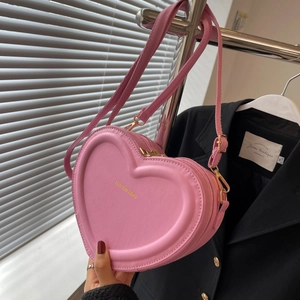 Dettaglio ravvicinato della borsa a tracolla rosa a cuore con scritte dorate