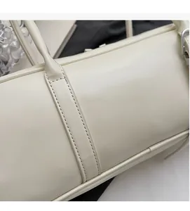 Detail showing smooth cream leather texture and stitching of the cylinder shoulder bag