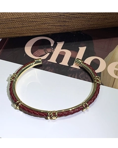 Dettaglio del bracciale in pelle intrecciata rossa e metallo dorato con fibbie