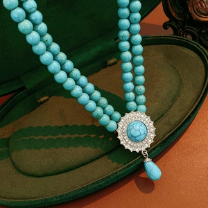 Close-up of double-layer turquoise bead necklace with rhinestone flower and water drop pendant