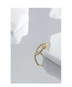 Macro shot of gold knotted S925 sterling silver ring on white stone with reflection