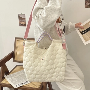 Détail d'un sac cabas matelassé blanc avec anses colorées et étiquette de marque