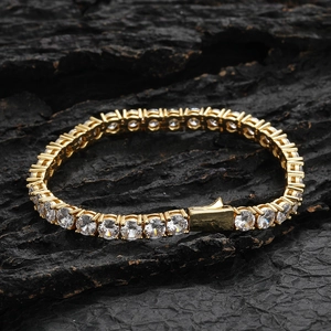 Gros plan du bracelet tennis doré serti de zircons ronds sur un fond noir texturé