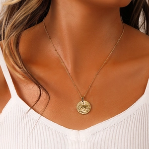 Macro shot of Taurus zodiac relief on a gold coin pendant necklace worn by a model