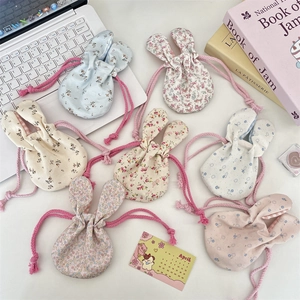 Flat lay of multiple floral bunny ear drawstring pouches in pastel colors with decor