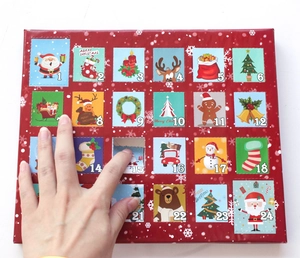 Main ouvrant la case 15 d'un calendrier de l'Avent de Noël rouge pour filles