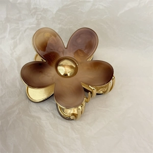 Detail of amber flower hair claw clip with golden metal base and marbled resin petals