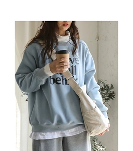 Detail of light blue oversized cotton sweatshirt with minimalist black letter print