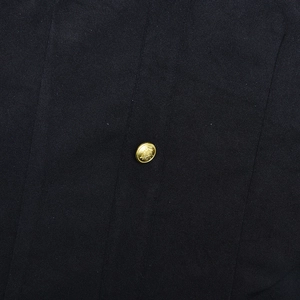 Detailed close-up of a gold embossed metal button on navy mesh patchwork dress