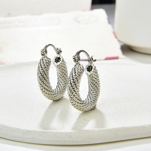 Silver twisted rope hoop earrings with textured metal weave on a minimalist pedestal