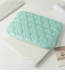 Macro detail of mint green quilted heart pattern on a padded laptop sleeve bag