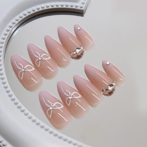 Pink gradient almond press-on nails with hand-painted bows and rhinestones