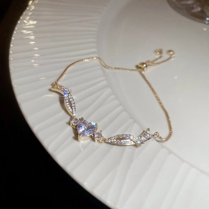 Detailed close-up of champagne gold heart zircon bracelet on a white textured porcelain plate