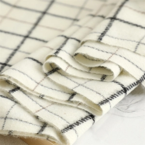 Close-up of soft white cashmere-like scarf fabric with black and brown plaid patterns