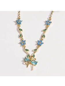 Details der Goldkette mit blauen Edelsteinblumen und einem eleganten Schleifenanhänger