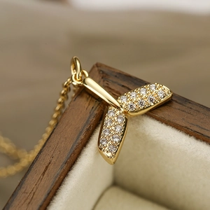 Collana dorata a coda di balena con zirconi posata su un portagioie in legno