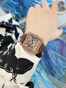 Detalle de reloj cuadrado dorado con bisel de diamantes y correa de cuero marrón