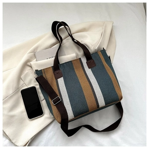 Macro detail of striped canvas tote bag texture with brown handles on a beige blazer